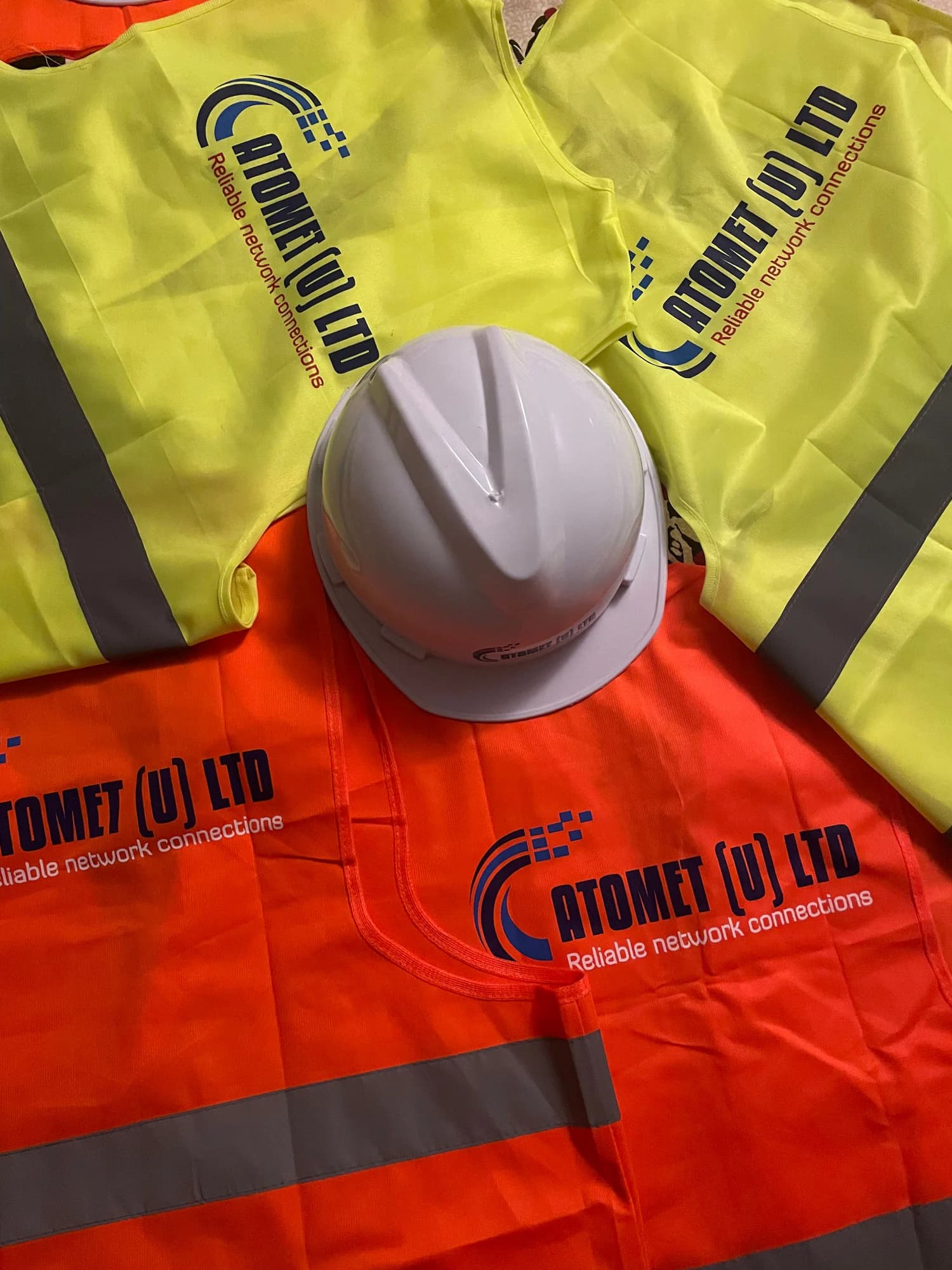 White Atomet hard hat on an orange hi-vis vest printed with the Atomet logo