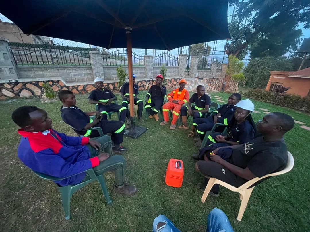 Atomet crew seated in a circle on garden chairs under an umbrella for a team briefing