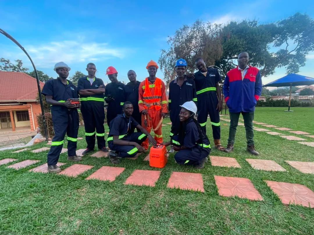 Atomet team group photo on a lawn, crew in navy coveralls and hard hats standing and kneeling with toolkits