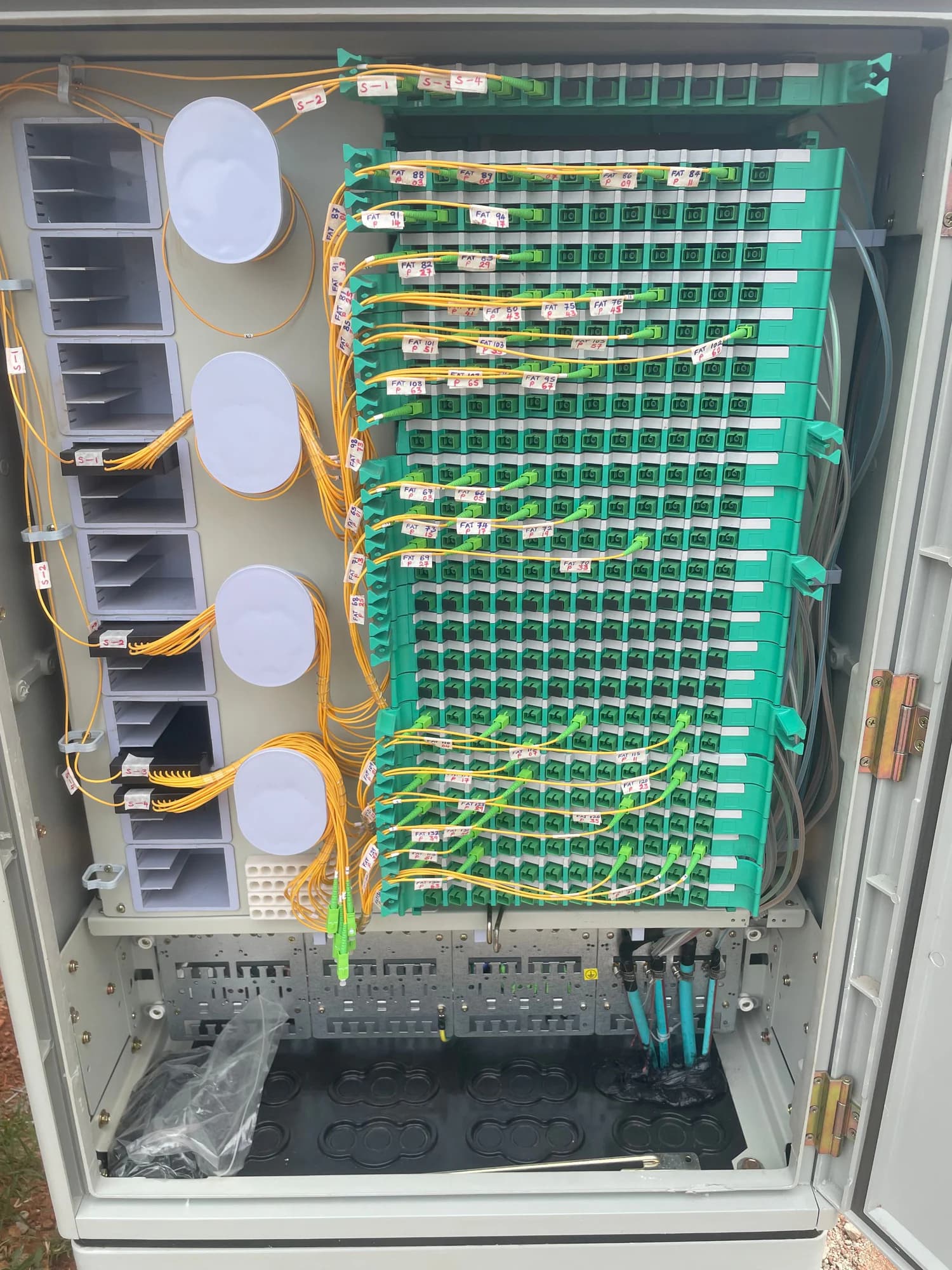 Fully patched fiber distribution hub with neatly routed yellow leads across a wall of green adapters
