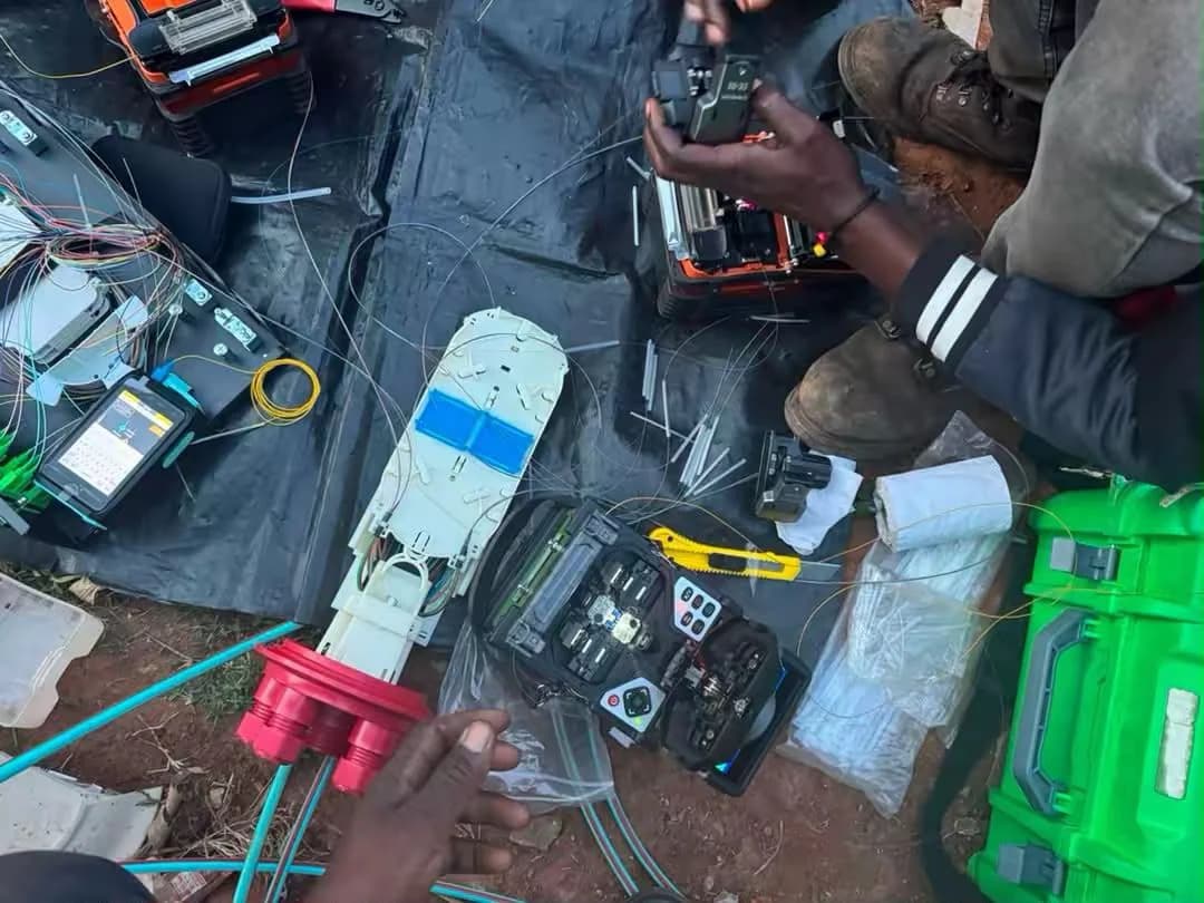 Overhead view of field splicing: a fusion splicer, an open closure, fiber strippers and cable laid out on a tarpaulin