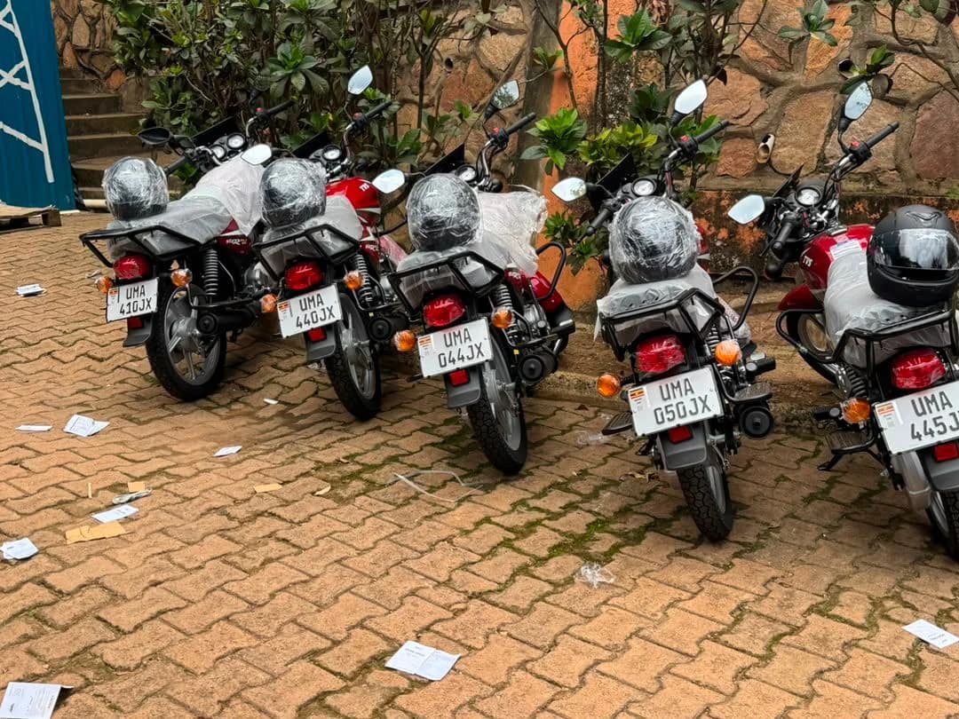 Row of new motorcycles with helmets on the seats, parked on brick paving