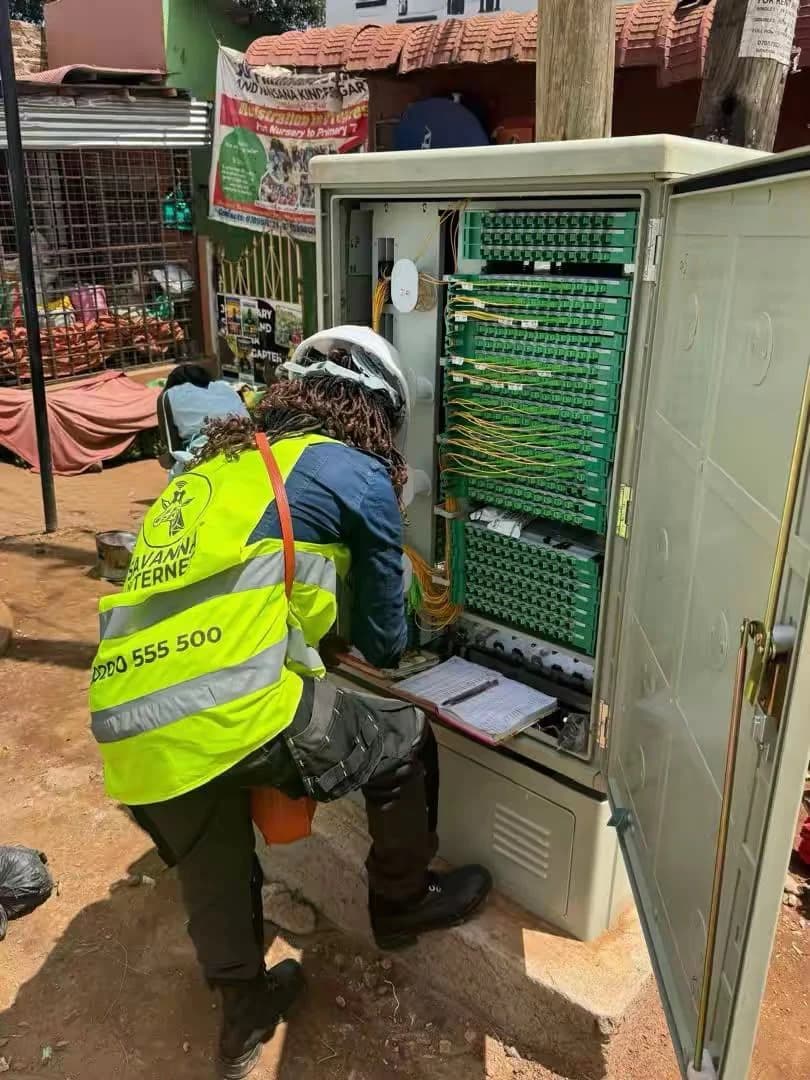 Atomet engineer writing port records on a clipboard beside a fully populated green fiber distribution frame