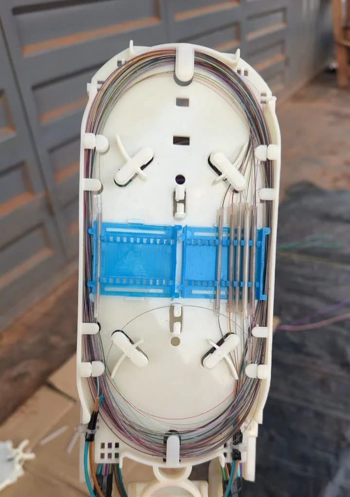 Close view of an opened fiber splice closure with coiled fibers and a blue splice holder in the tray